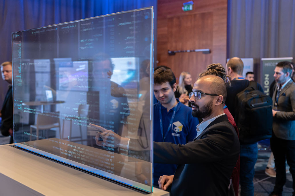Photo of a man pointing at some code on a translucent screen in the EuroHPC Demo Lab at the 2023 Summit