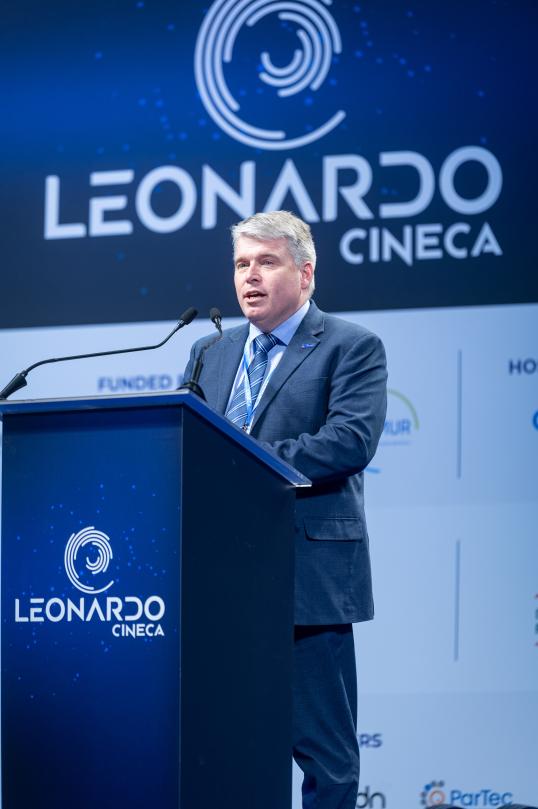 anders dam jensen making his speech at the podium, with the leonardo logo displayed behind him in large white lettering on a blue background